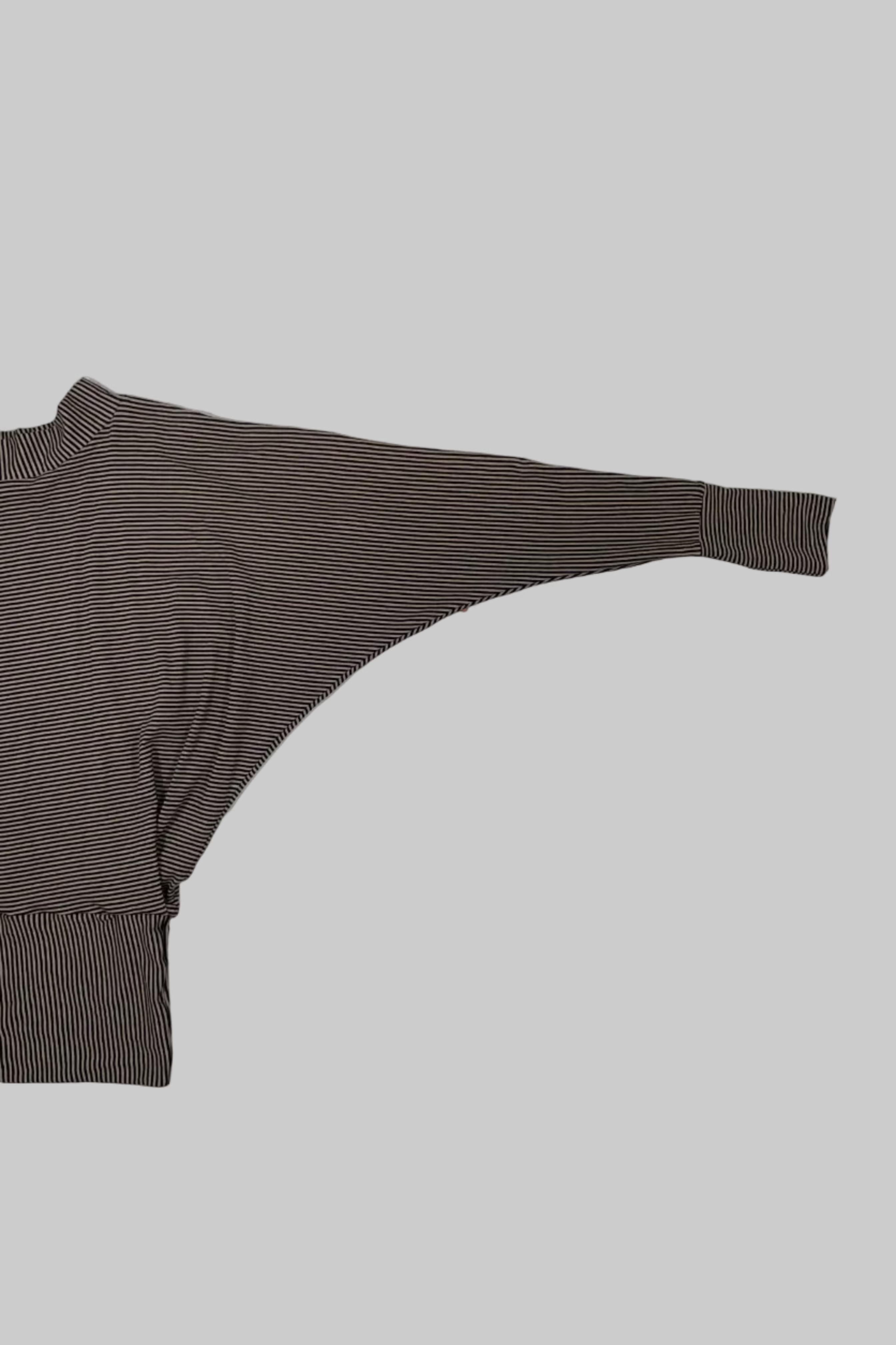 A brown and white striped knit garment laid flat on a white wooden floor.