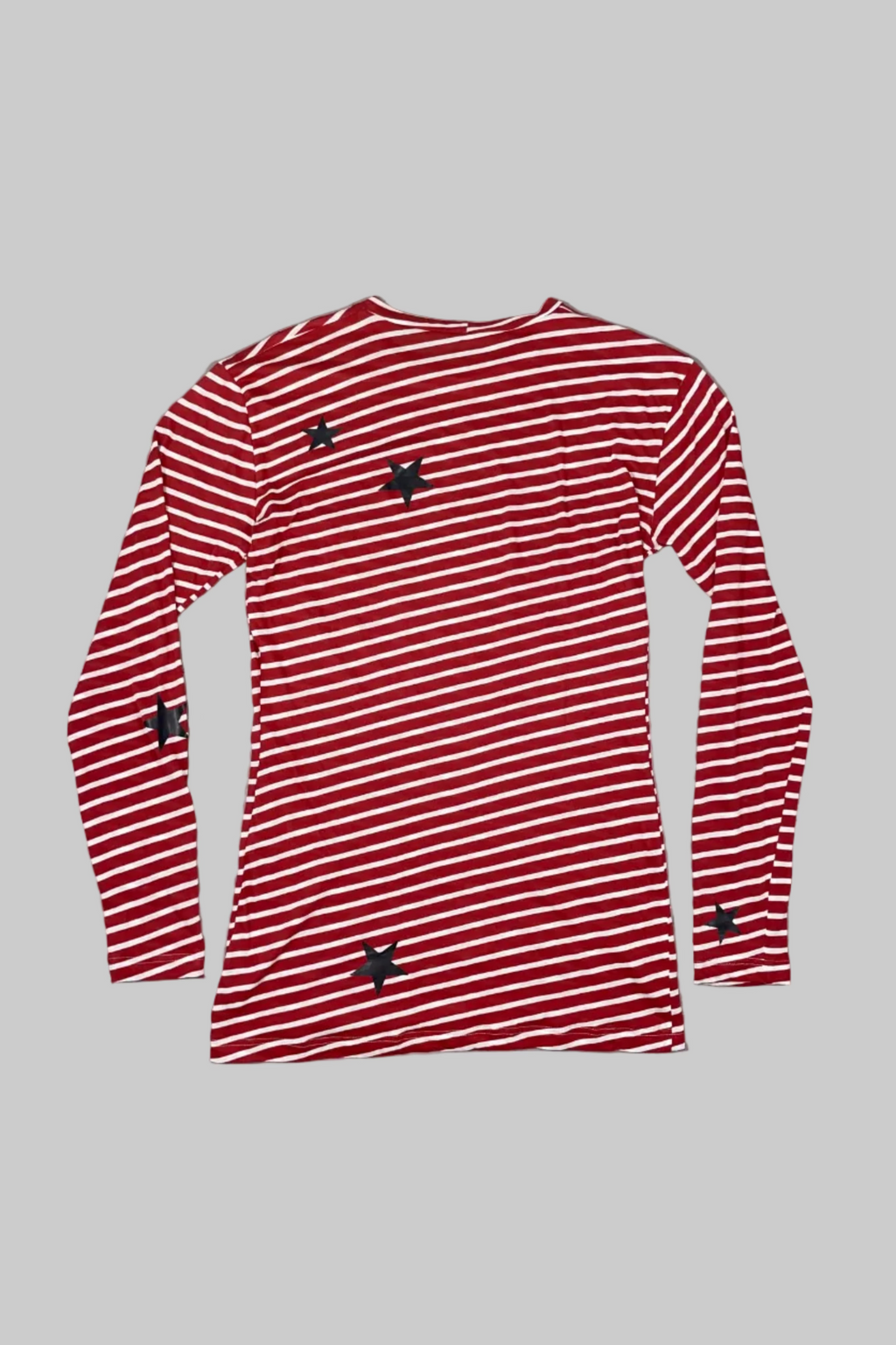 A red and white striped long-sleeve shirt with small black star details, laid flat on a white wooden plank background.