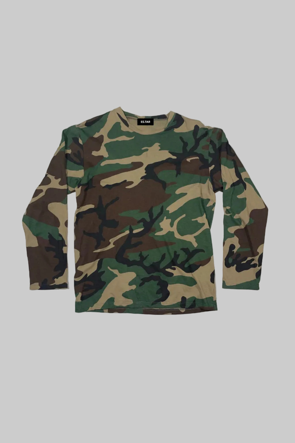 A long-sleeve crewneck shirt in a classic woodland camouflage pattern, laid flat against a white-painted wooden plank background.