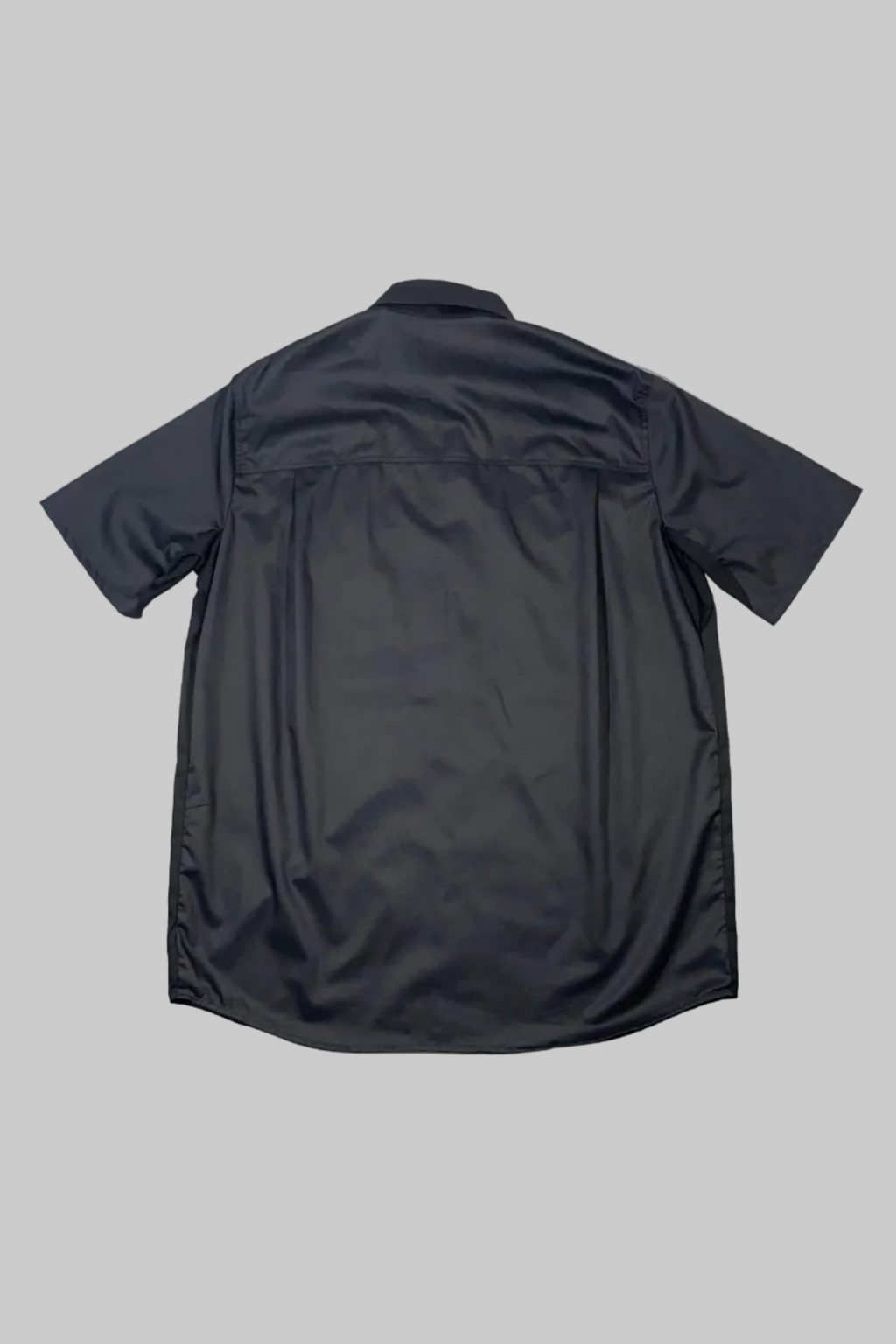 A dark charcoal gray short-sleeve button-up shirt shown from the back, laid flat on a white painted wooden plank surface.