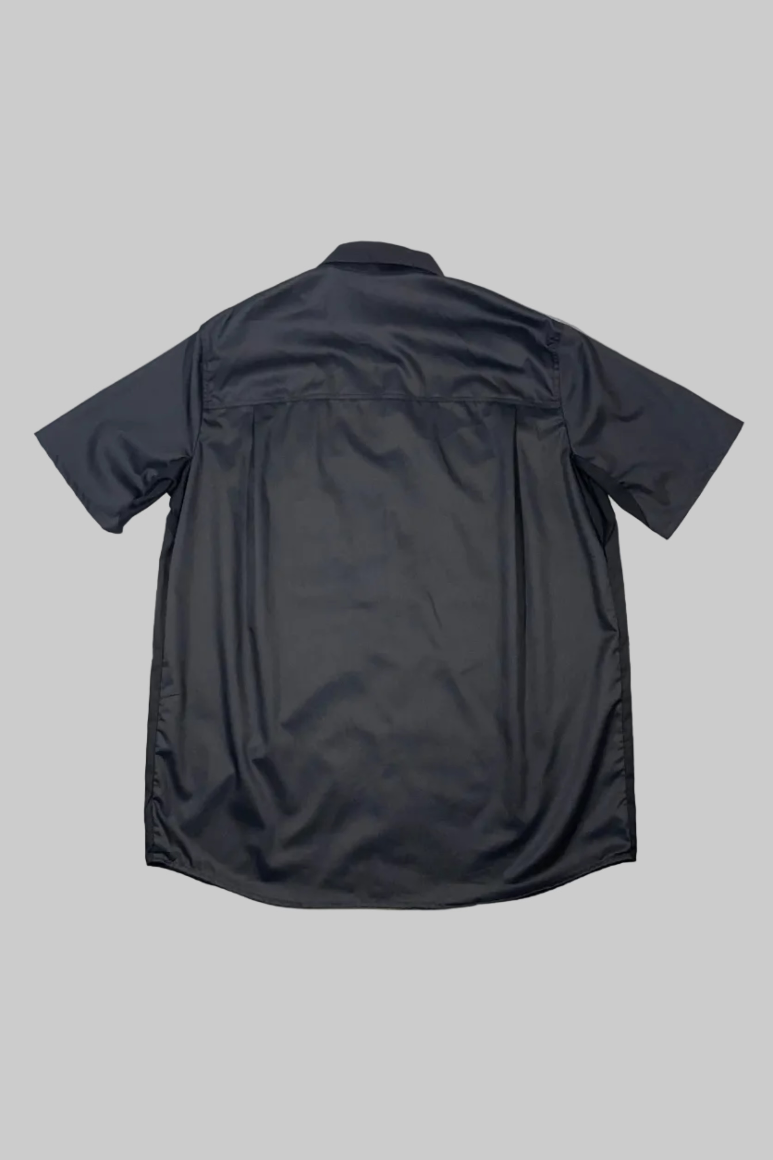A dark charcoal gray short-sleeve button-up shirt shown from the back, laid flat on a white painted wooden plank surface.