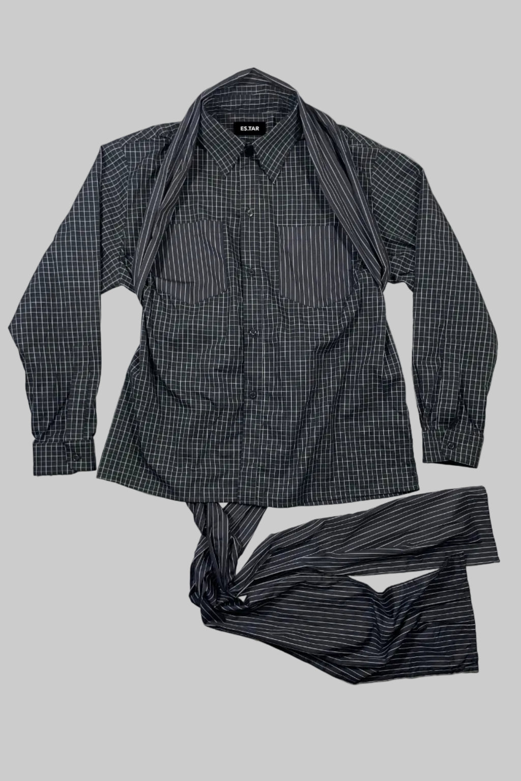 A men's long-sleeve button-up shirt in a dark gray and black micro-check pattern, styled with matching striped pants laid out on a white wooden background.
