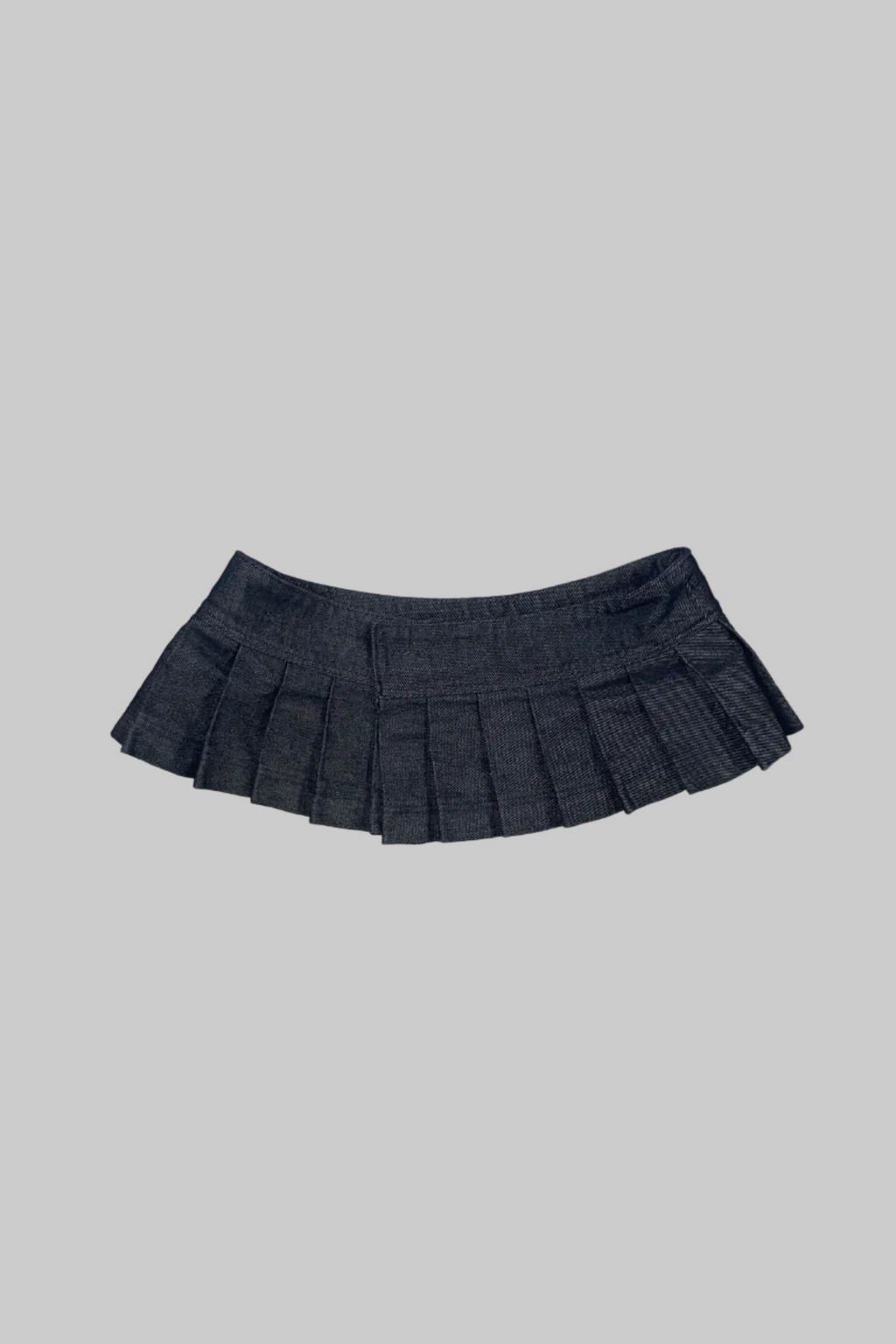 A dark gray pleated mini skirt with a subtle plaid pattern, laid flat on a distressed white wooden floor.