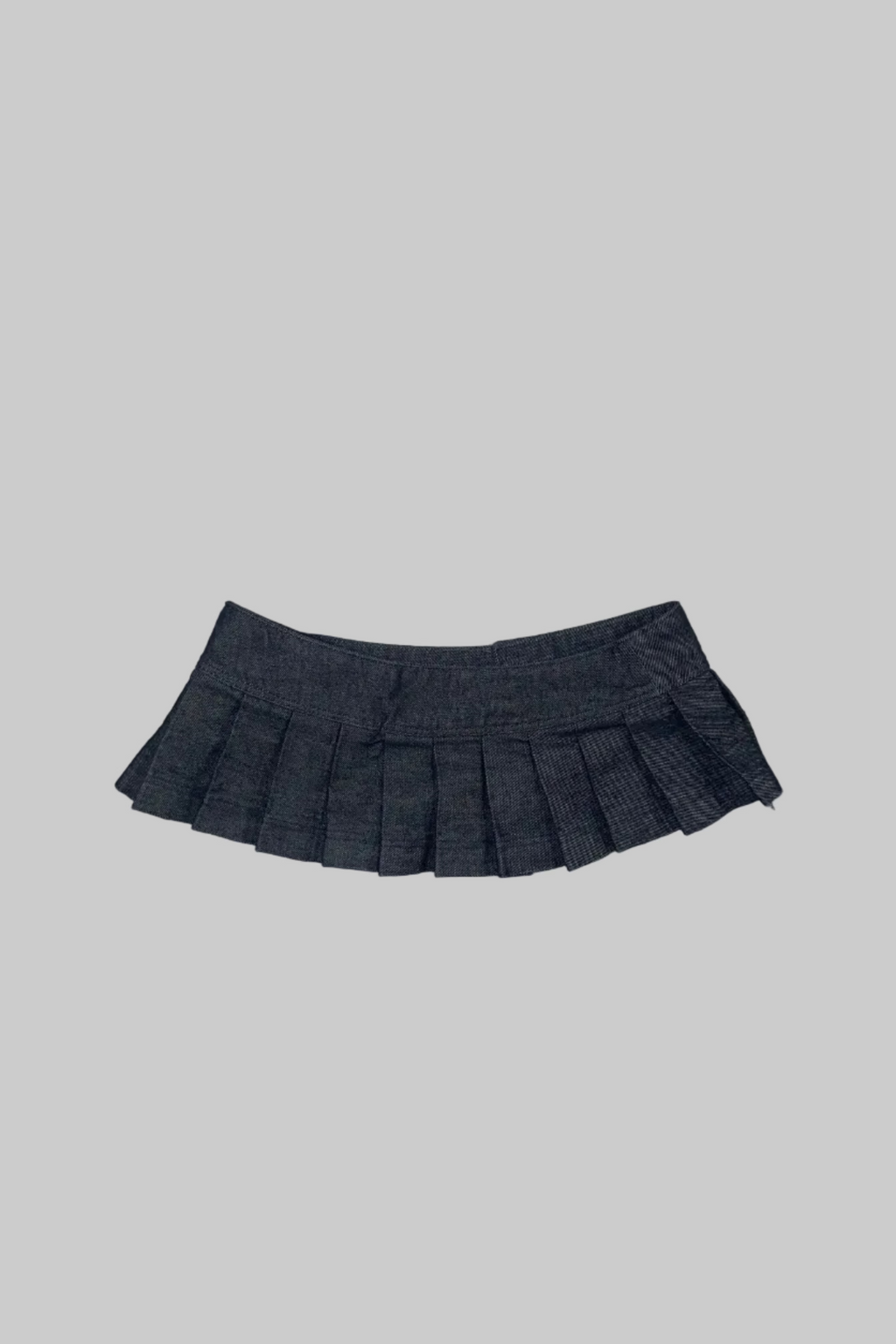A dark gray pleated mini skirt laid flat on a white wooden plank surface.