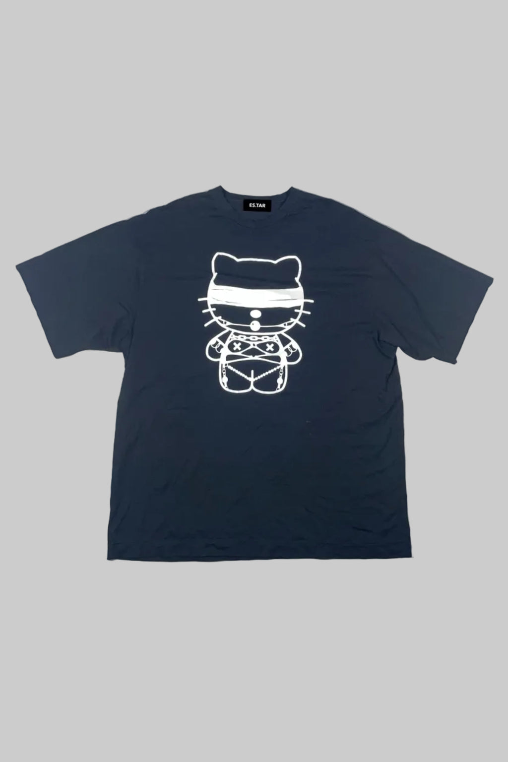 A navy blue short-sleeve t-shirt with a white line art graphic of a cat wearing a headband and patterned shirt, laid flat on a white painted wooden plank background.