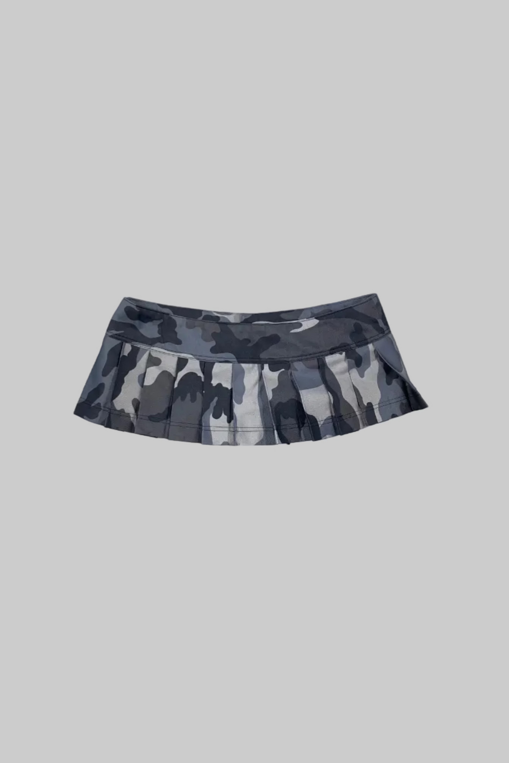 A gray and black camouflage pleated athletic skirt laid flat on a white wooden plank surface.
