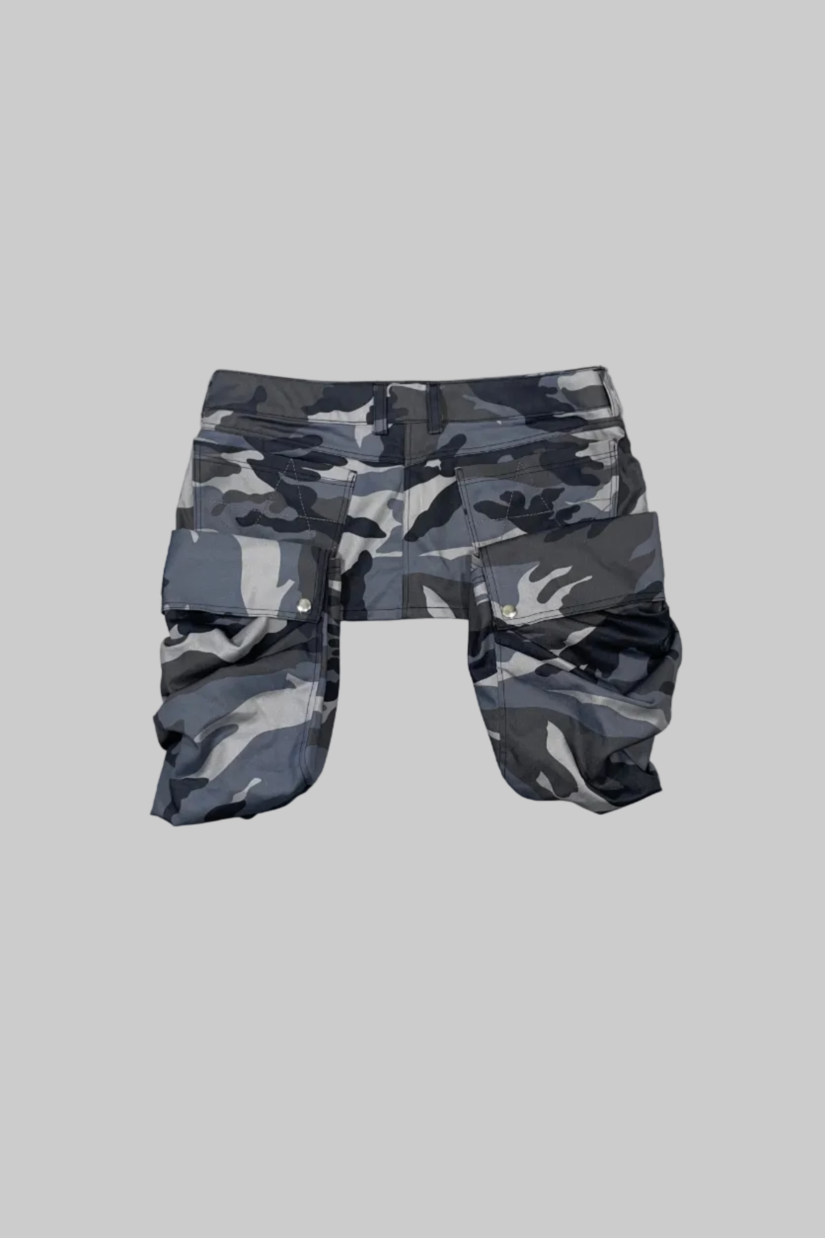 Gray and black camouflage cargo shorts laid flat on a white wooden floor.