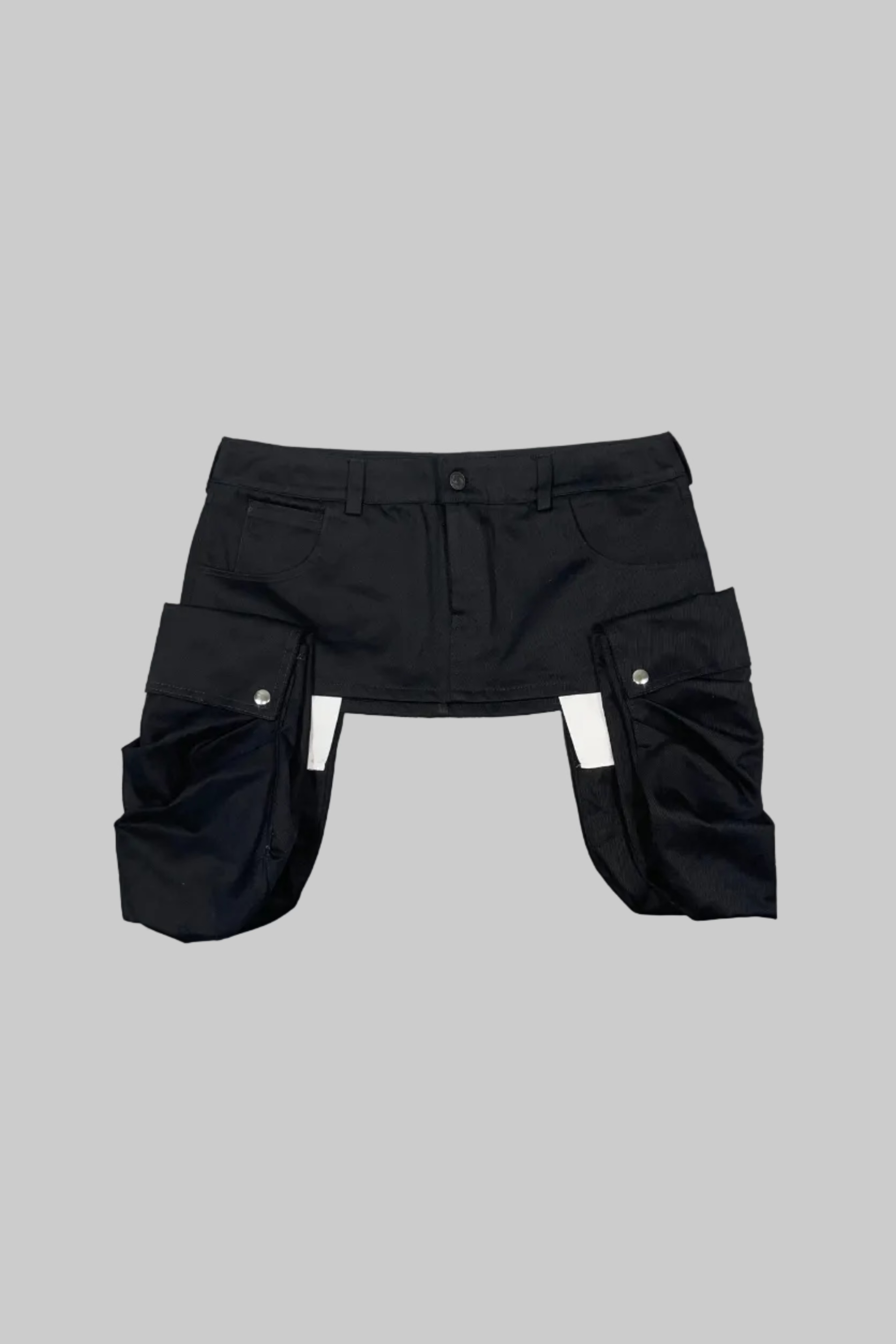 Black cargo shorts with a unique split leg design, laid flat on a light gray wooden floor.