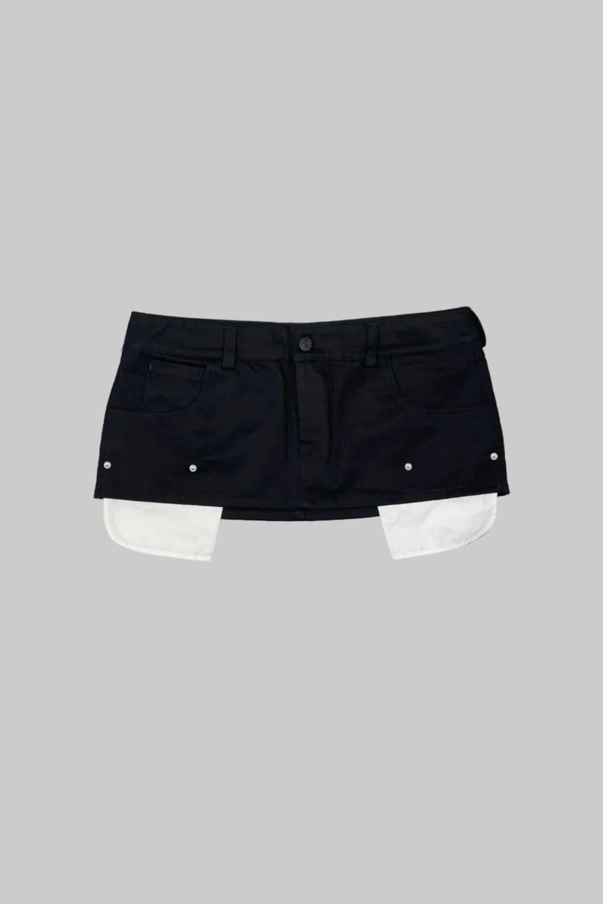 A black denim mini skirt with white contrast panels folded out from the hem, laid flat on a gray wooden plank background.