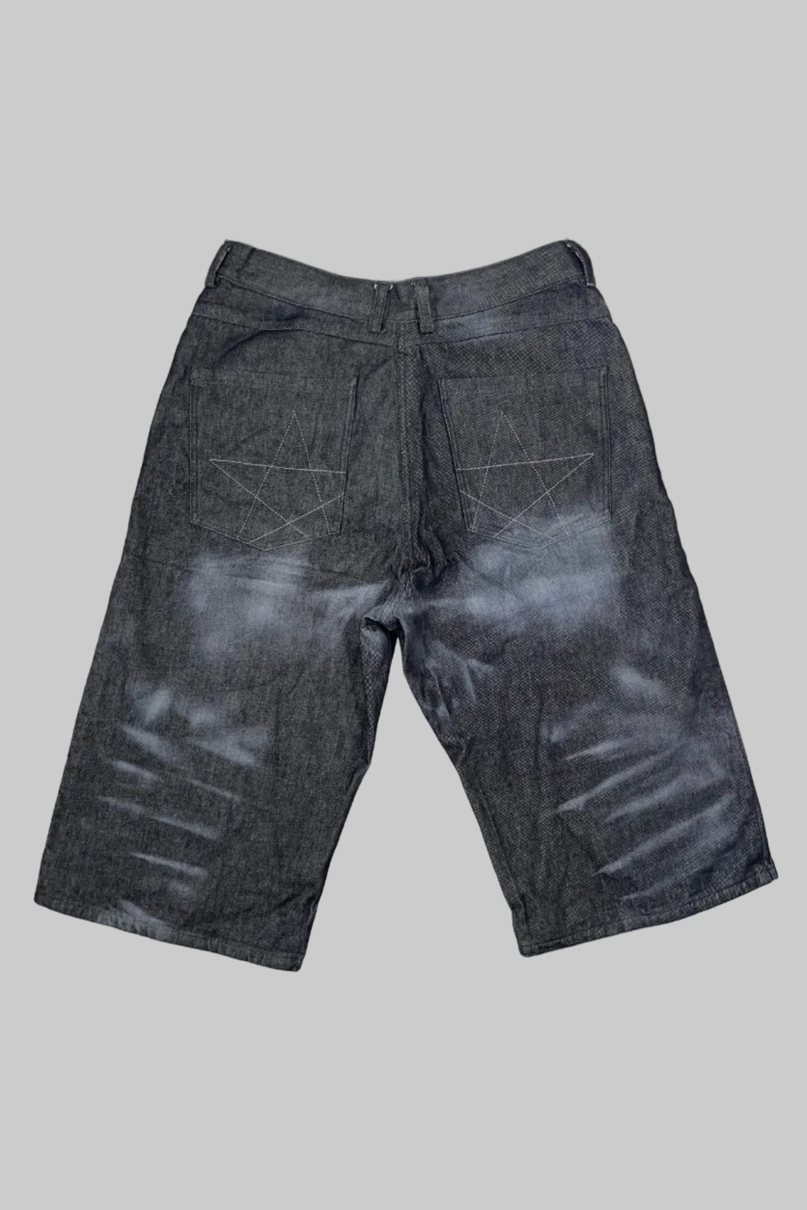 Dark gray washed denim shorts with a faded white distressed pattern, laid flat on a white wooden plank floor.