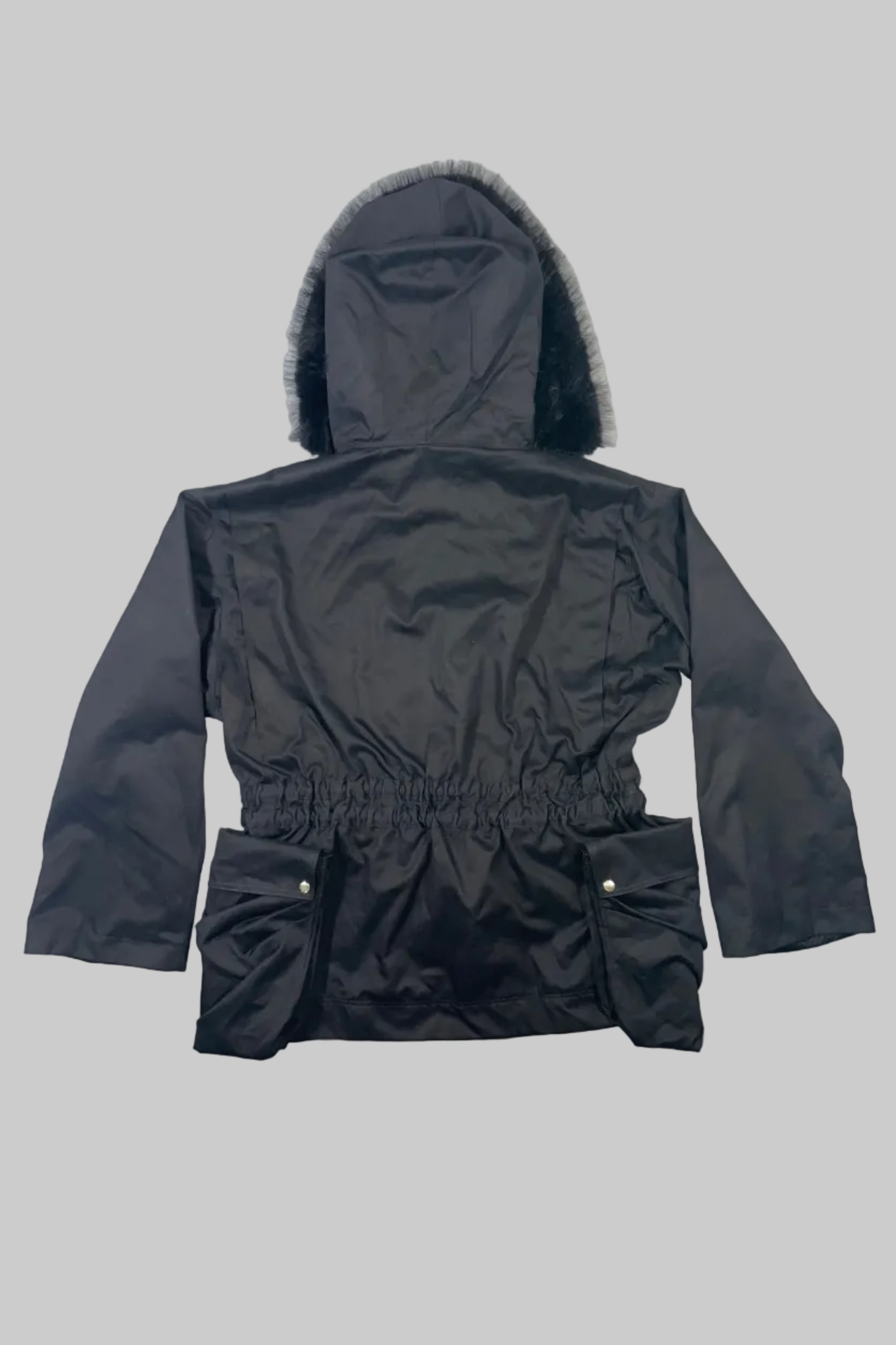 A black hooded winter jacket with a faux-fur trimmed hood and an elasticated waist, laid flat on a white wooden plank surface.